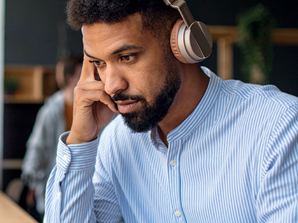 Man with headphones studying at a laptop.
