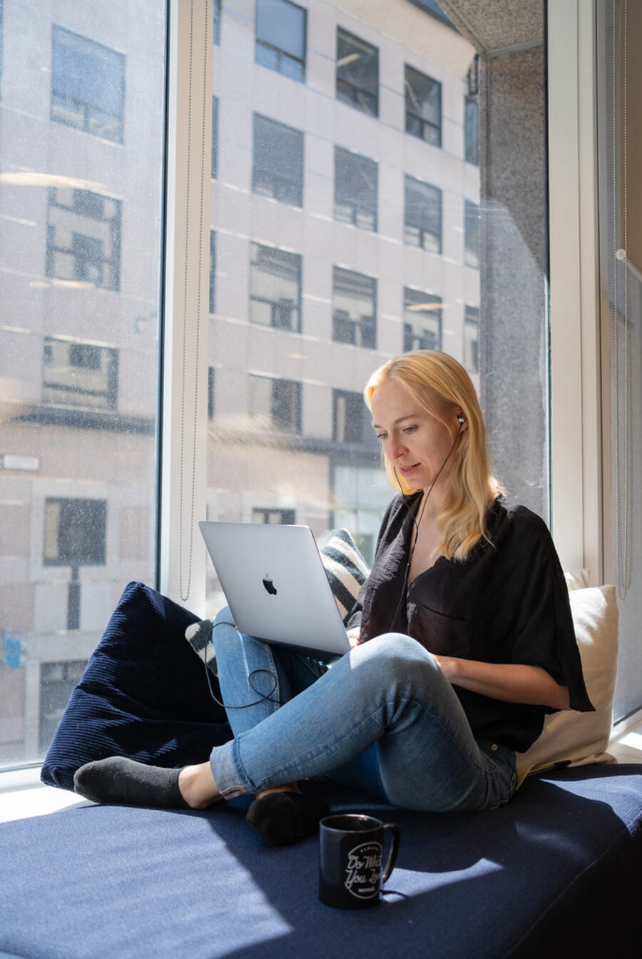 A person listening on earbuds while reading on a laptop.