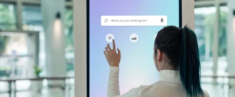 Person interacting with a digital touchscreen in a modern, open space with vibrant colors.