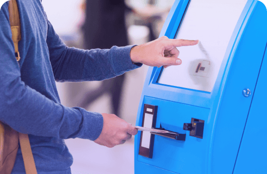 Person using a blue self-service kiosk, inserting a card for transaction assistance.