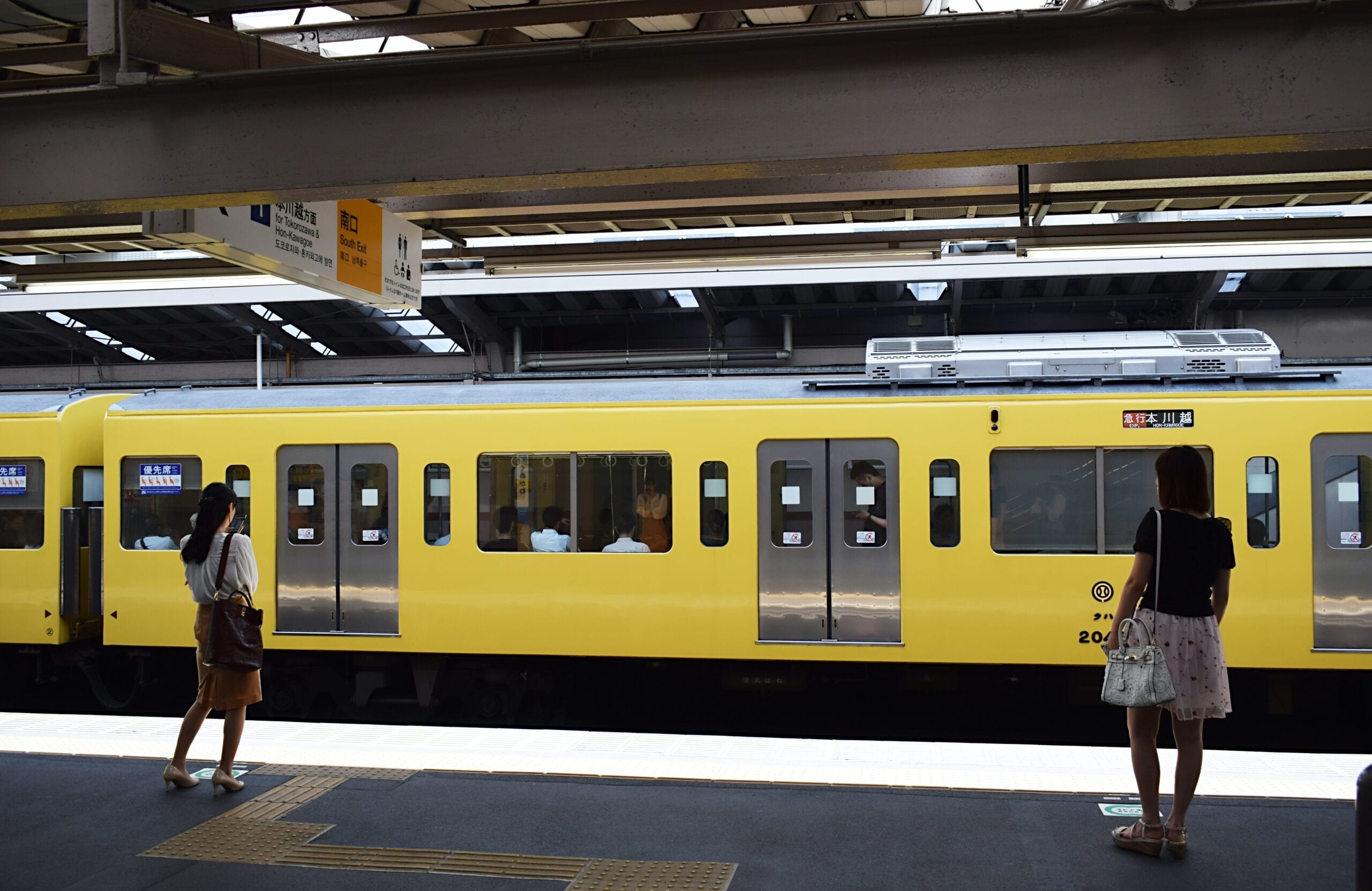 A train stopped at a station platform in Japan, passengers waiting
