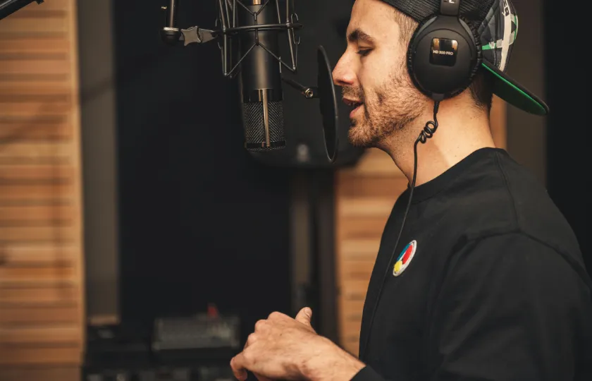 Un homme enregistre sa voix avec un microphone dans un studio.