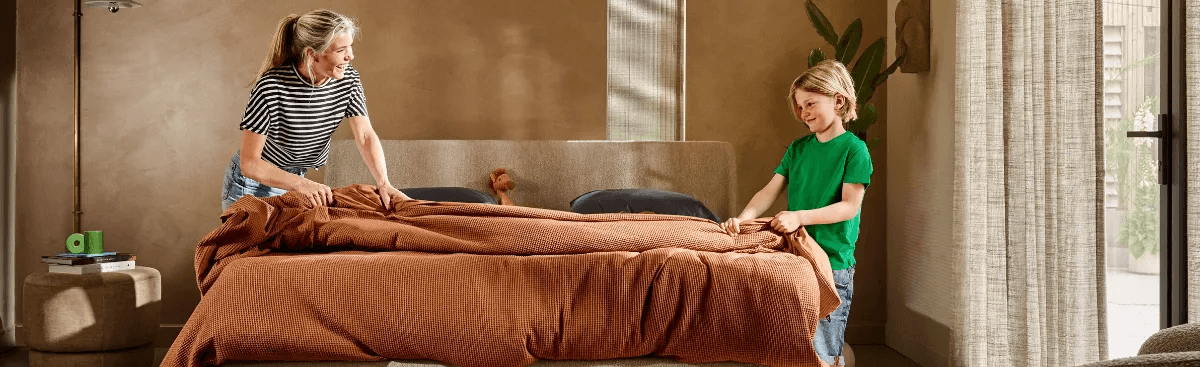 Een vrouw en een kind maken een bed.