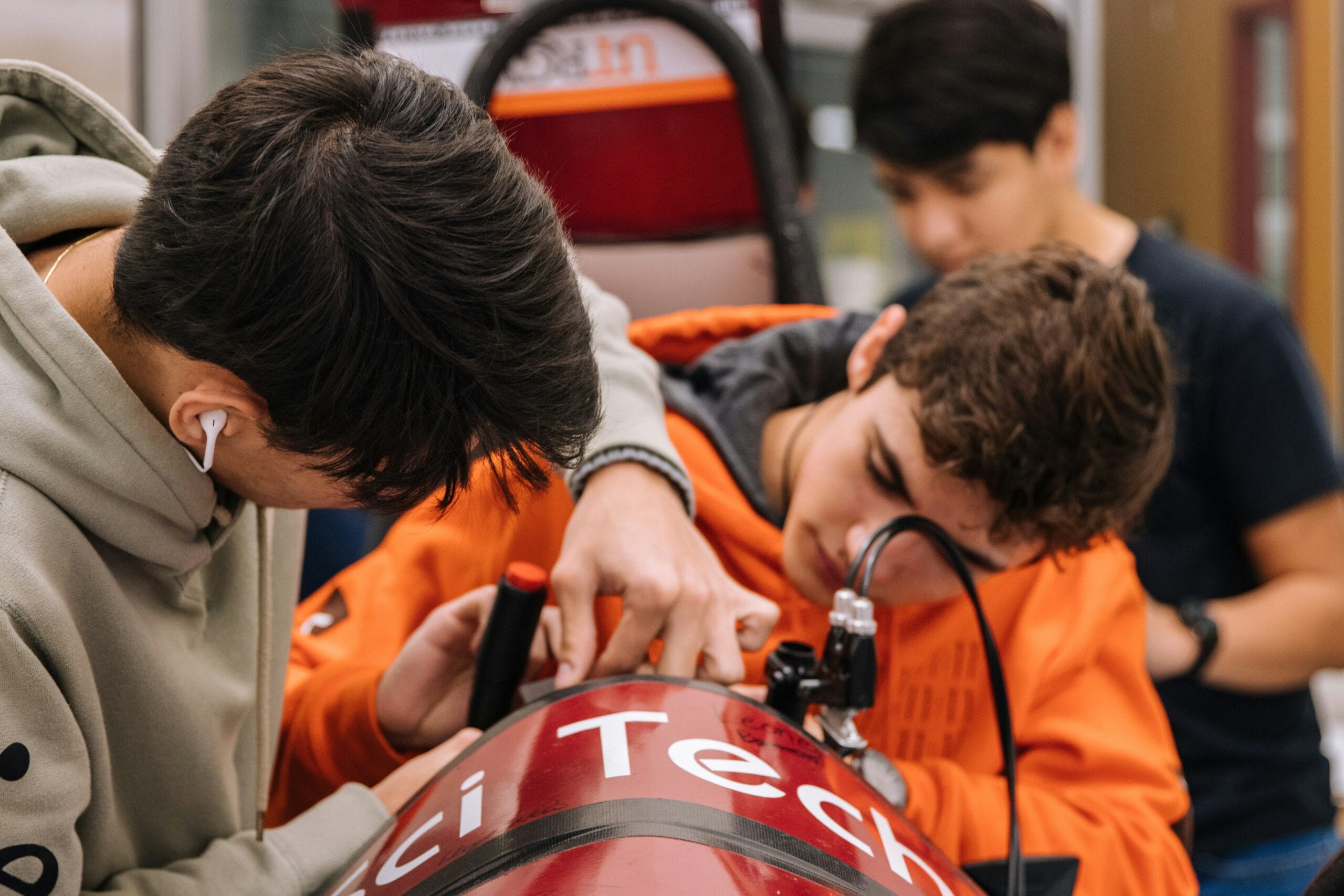 Due apprendisti maschi che lavorano fianco a fianco sulla meccanica di auto da corsa.
